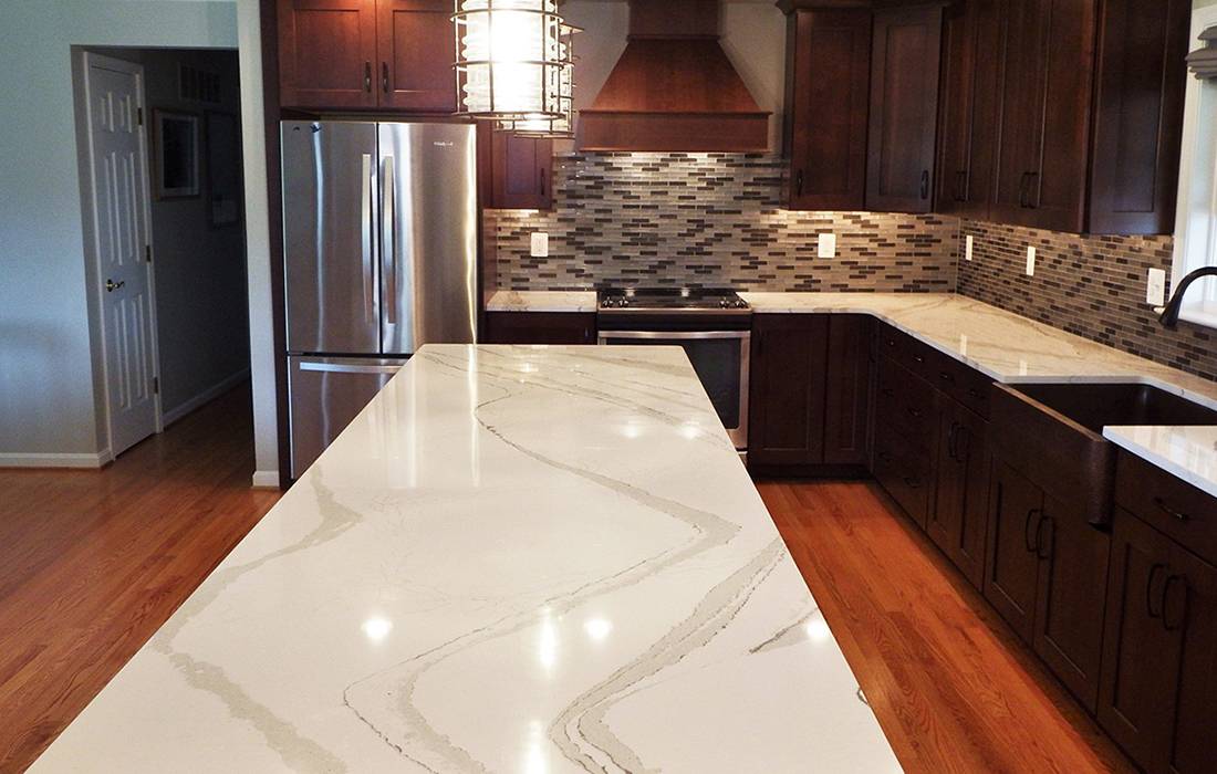 remodelled kitchen with white marble counterss, an island, new cabinets, & a backsplash