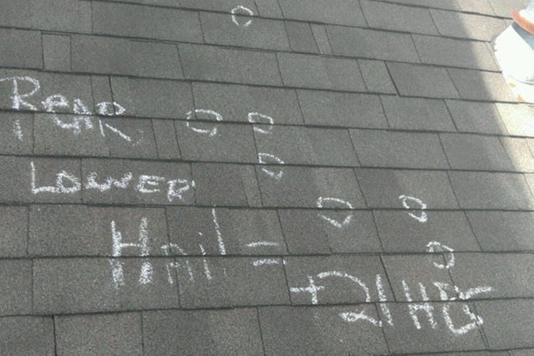 a shingled roof with hail damage circled in chalk