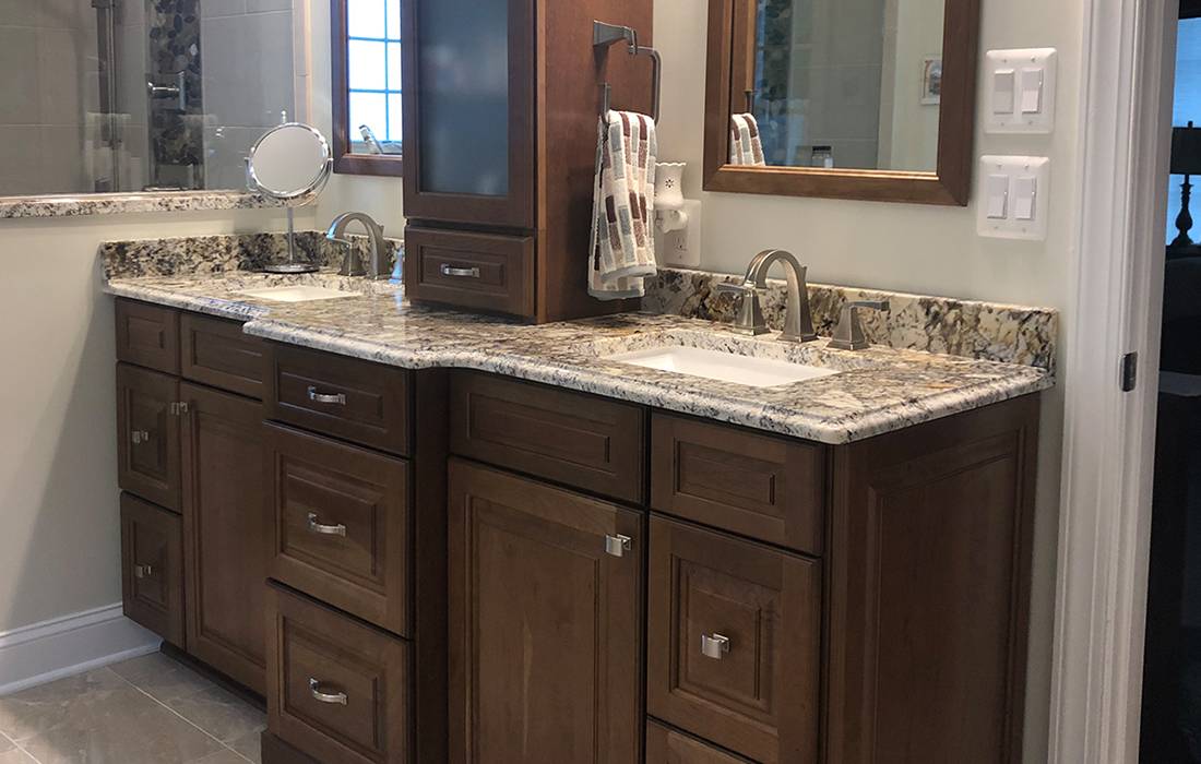 a bathroom vanity sink with a granite counter, new cabinets, & modern faucets