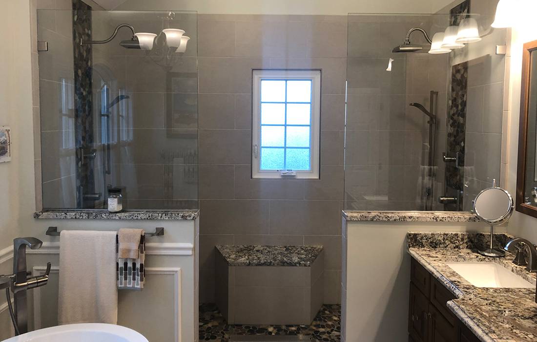 remodelled bathroom with granite counters, glass-walled shower, & tiling