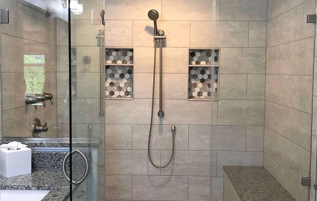 Redone shower with grey large tile walls and a free hand showerhead