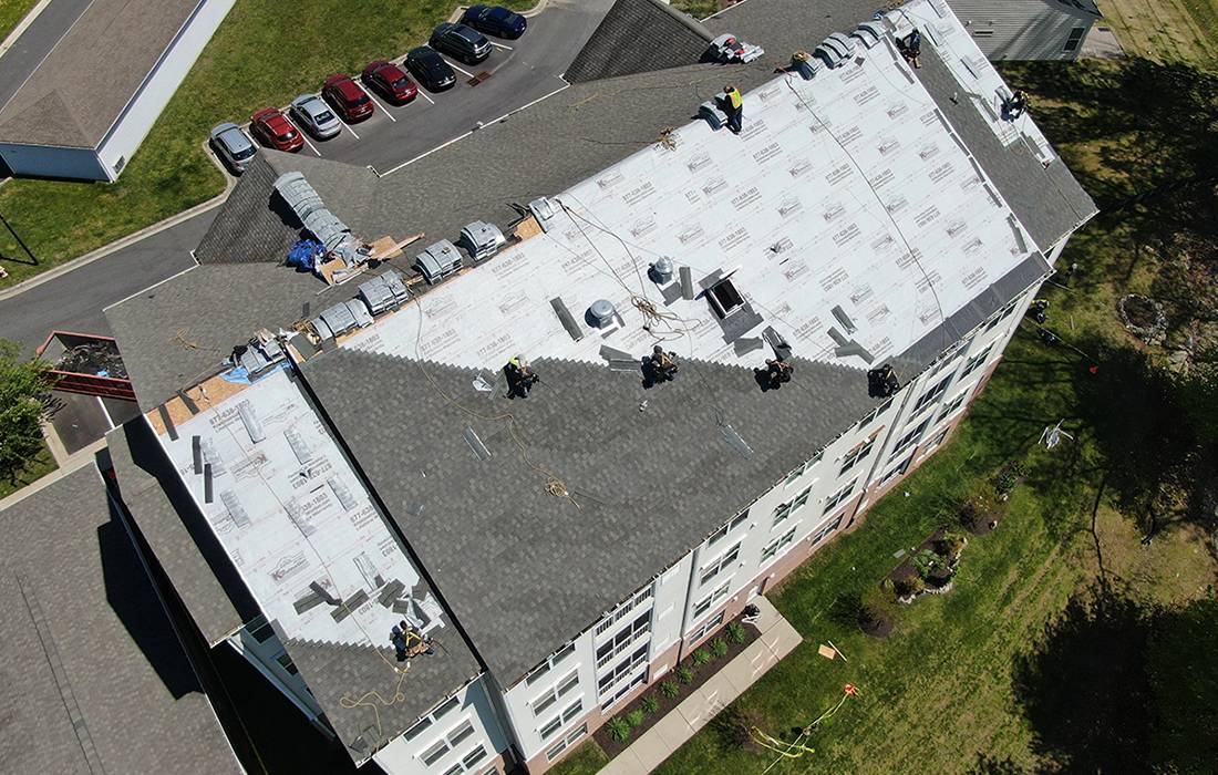 Kris Konstruction workers shingling the roof of an apartment building