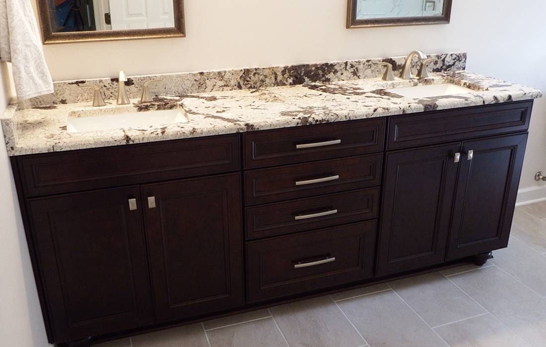 Granite two sink bathroom counter with dark wood cabinets