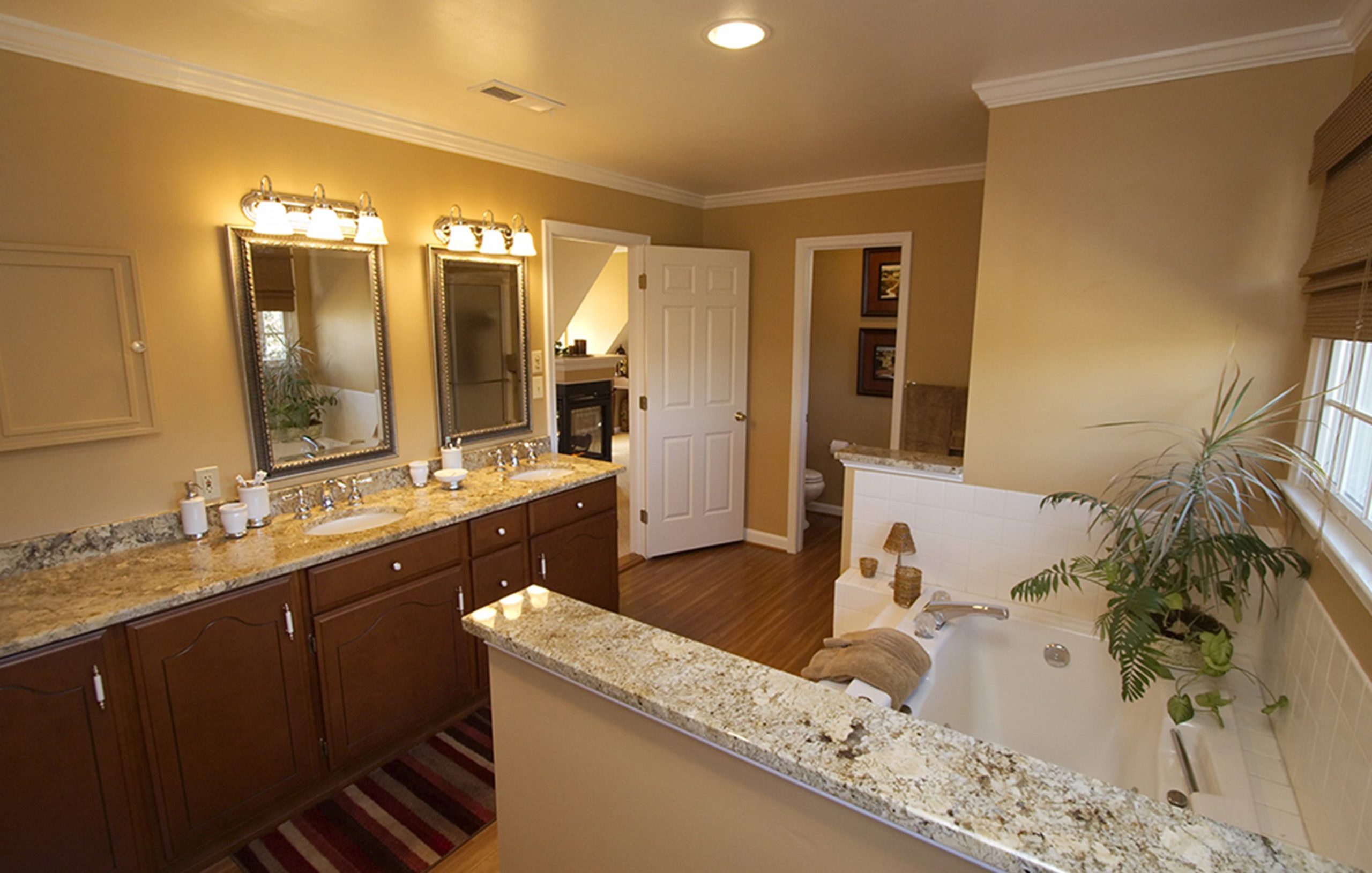 a remodelled bathroom with a granite vanity sink, hardwood floors, & a new bathtub