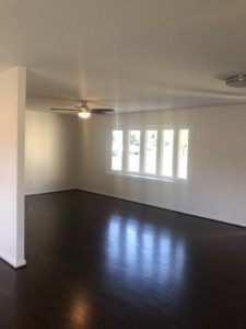 Living room with new flooring, drywall, fixtures, and more after being restored from a fire.