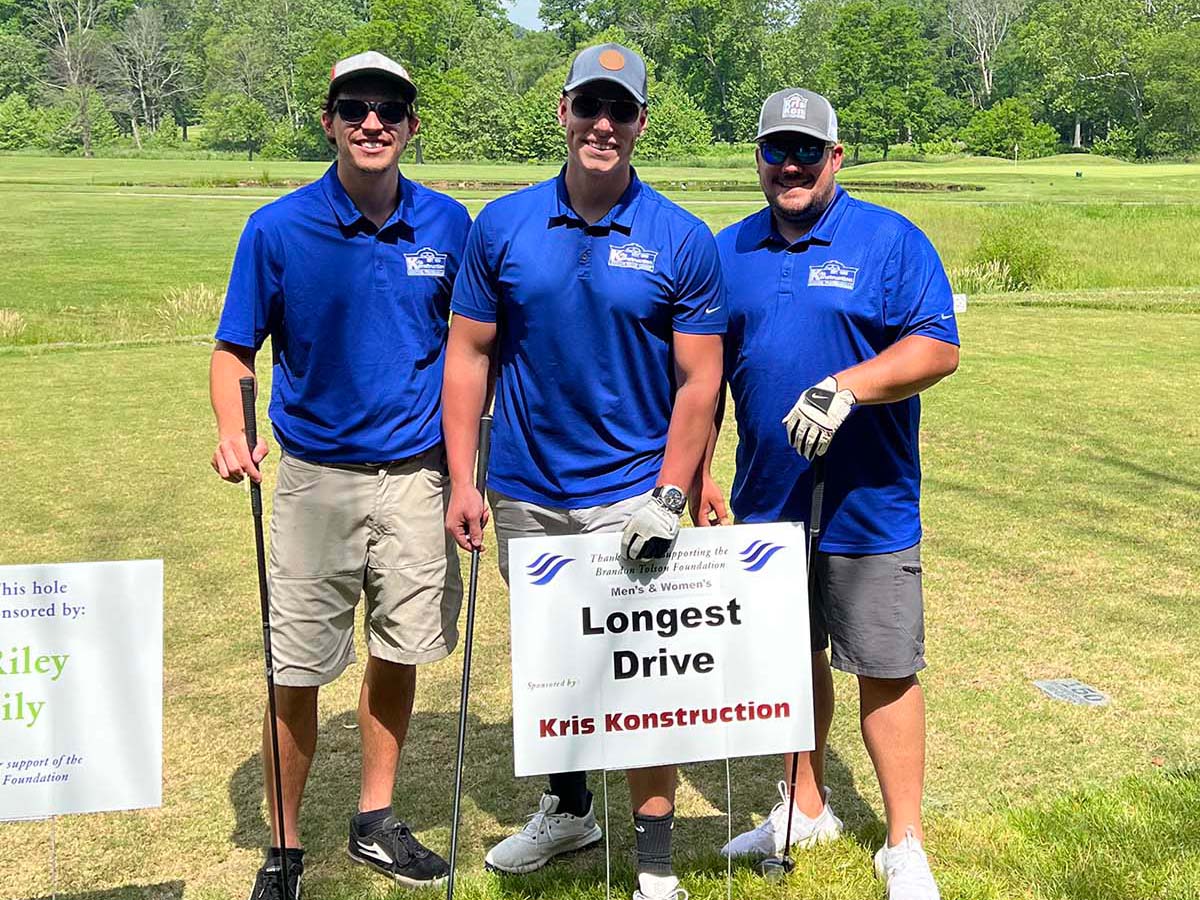 three smiling Kris Konstruction employees at a charity golf tournament