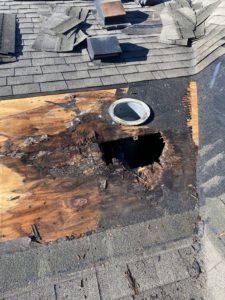 View of a damaged roof. Large hole and rotting materials shown due to water damage.