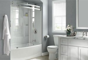 Remodeled white bathroom with combination tub and shower, toilet, and white vanity.