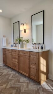 Primary suite modern vanity with herringbone floors
